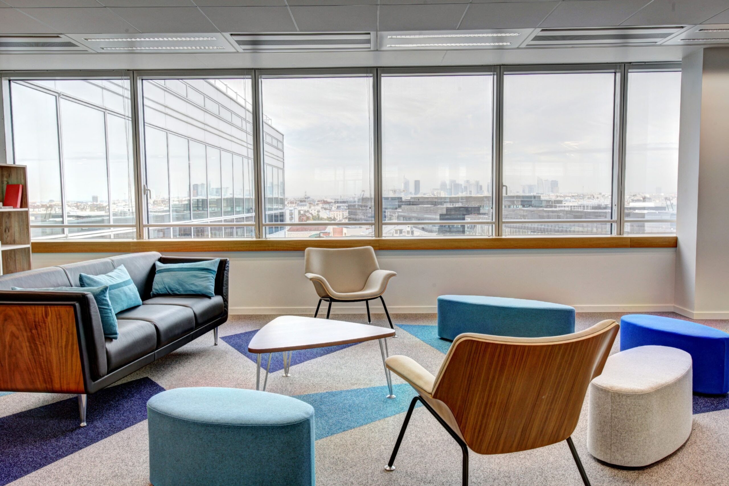 Colorful furniture adds a lively touch to this office, which benefits from ample sunlight streaming through a large window.